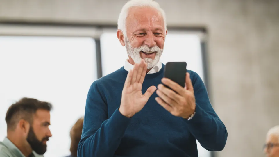 Homem mais velho sorrindo enquanto usa o celular