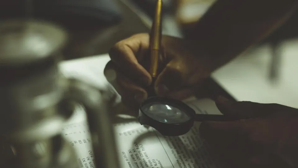 Pessoa examinando um documento com uma lupa