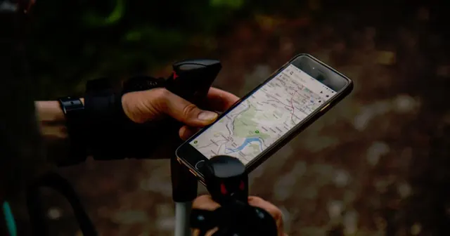 Mão segurando celular com um mapa aberto ao ar livre