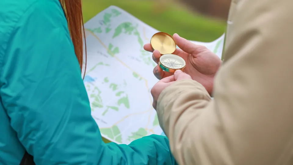 Duas pessoas consultando um mapa de papel e uma bússola