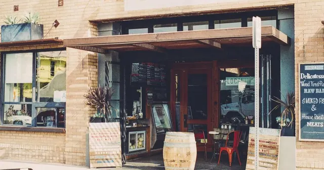 Fachada de restaurante com mesas e barris na calçada