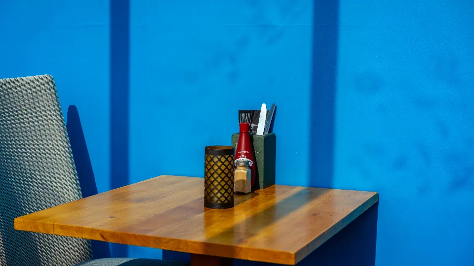 Mesa de restaurante vazia junto a uma parede azul