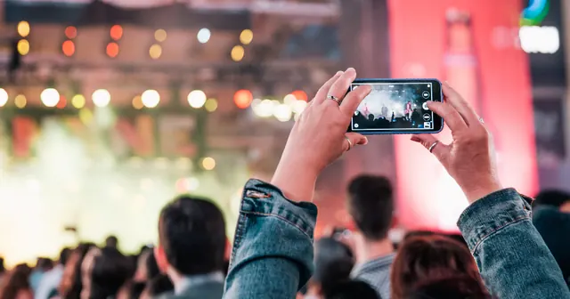 Público num show, com uma pessoa erguendo o celular
