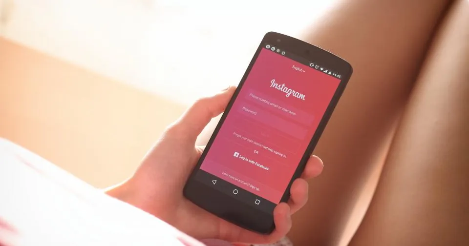 Mão segurando celular com a tela do Instagram aberta